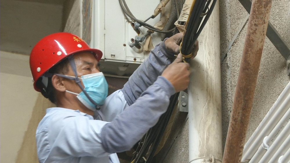 圖為施工人員在老舊小區(qū)（向陽(yáng)小區(qū)）對(duì)空中纜線進(jìn)行捆綁.jpg