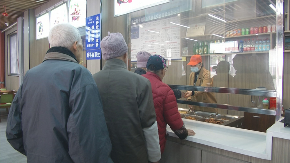 圖為張朝麗為老人打飯菜.jpg