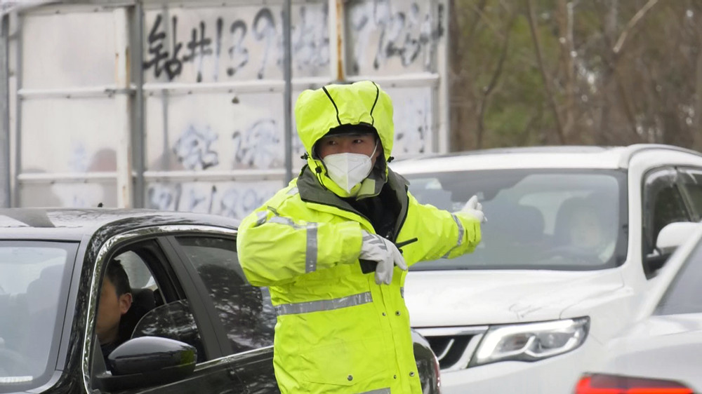 圖為正在車流中頂風(fēng)冒雪指揮交通的交警.jpg