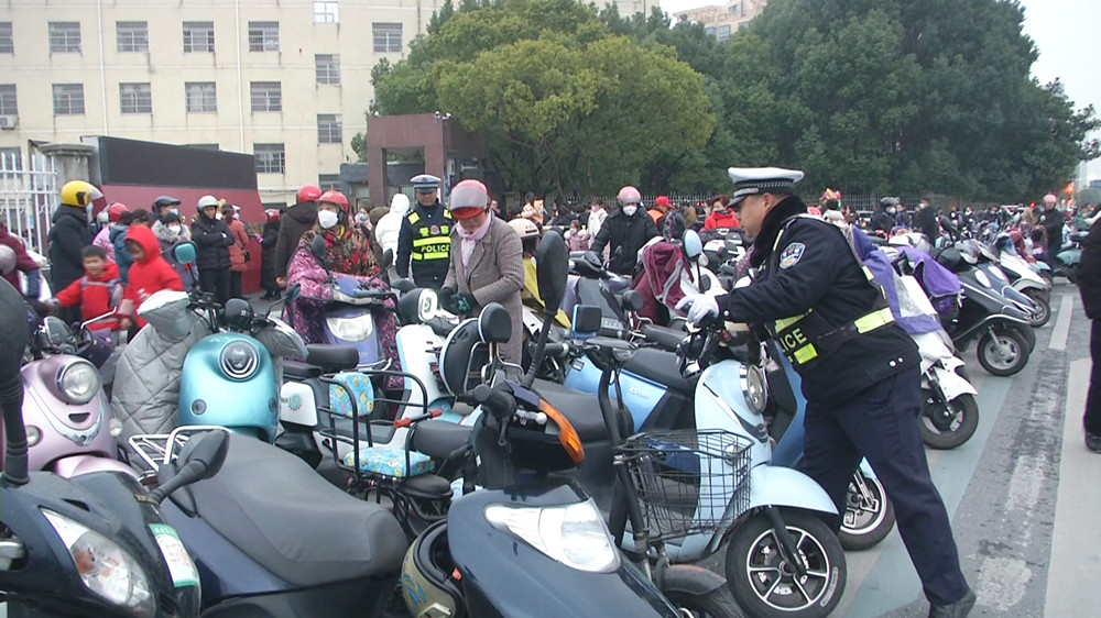 交警護(hù)學(xué)崗  交警在整理亂停放的電瓶車.jpg