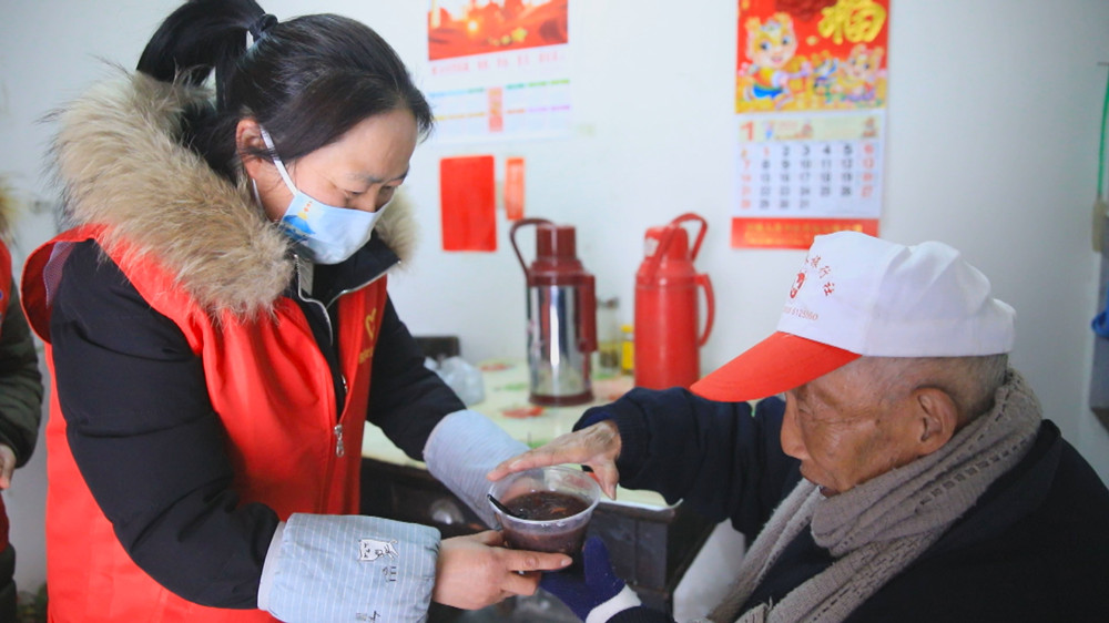 圖為社區(qū)志愿者上門送粥給行動不便的居民.jpg