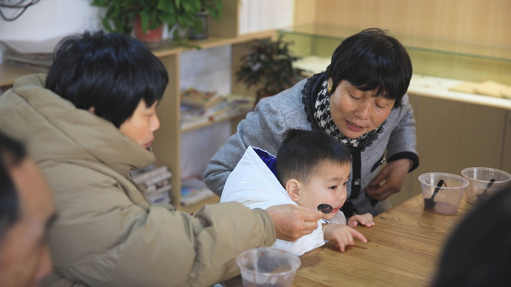 圖為社區(qū)居民正圍坐一起吃臘八粥，感受濃濃節(jié)日氛圍2.jpg