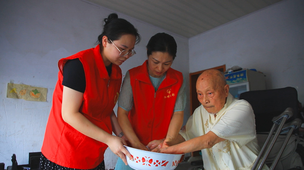圖為社區(qū)志愿者正在部分行動不便的退伍軍人家長開展關(guān)愛服務(wù).jpg
