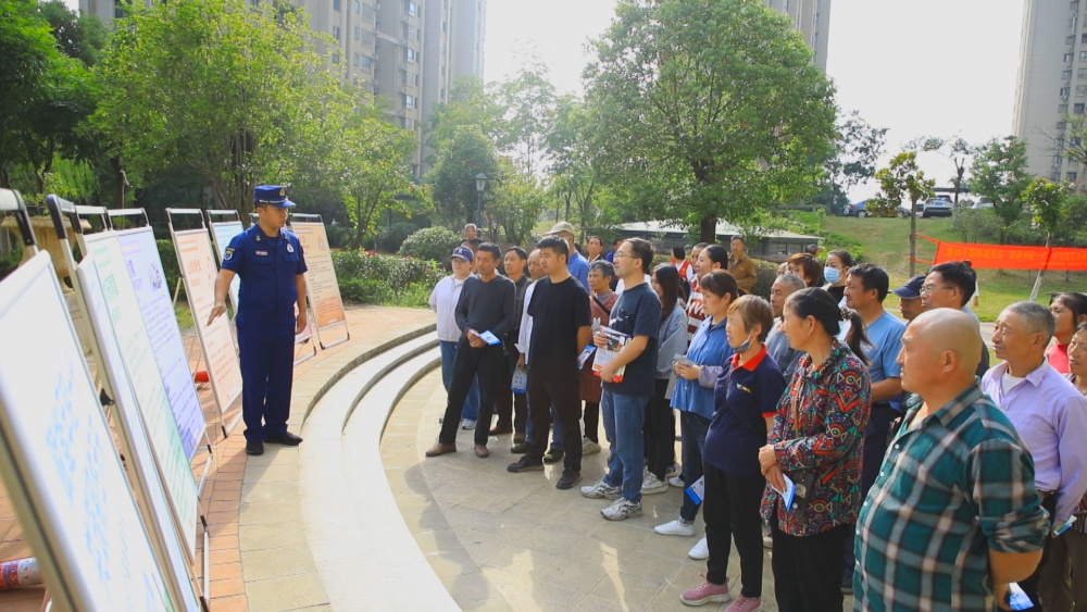 圖為消防員正在結(jié)合展板為小區(qū)居民講解防災(zāi)減災(zāi)自救知識(shí).jpg