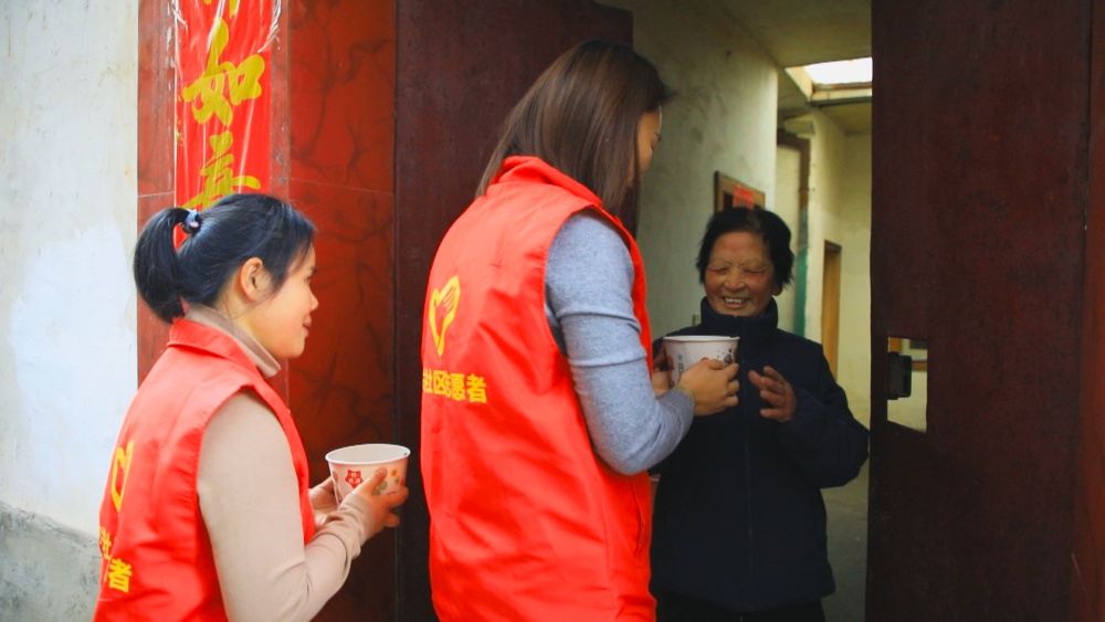 圖為社區(qū)志愿者為轄區(qū)老人送上臘八粥.jpg