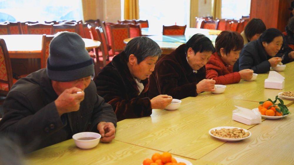 圖為社區(qū)居民正在品嘗美味的臘八粥.jpg